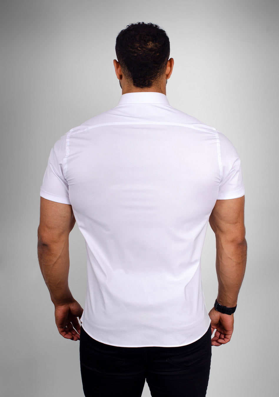 White short sleeve athletic fit shirt on an athletically built model, showcasing the muscle fit design that enhances physique, with stretch fabric for comfort and mobility